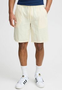 Beige shorts met een elastische tailleband en trekkoord. Gemaakt van lichte stof, met zijzakken en een ontspannen pasvorm.