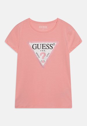 Világos rózsaszín pamut pöttyös póló, háromszög alakú fekete-fehér logóval, strasszkövekkel, rövid ujjakkal és kerek nyakkivágással.