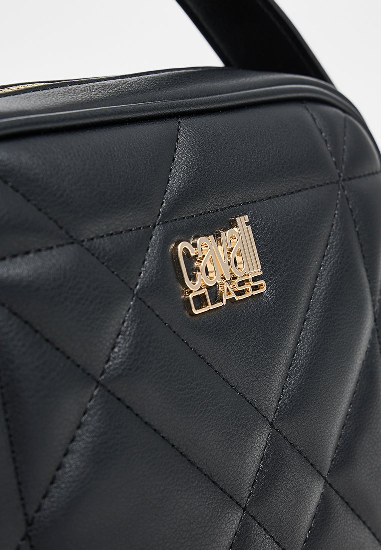 Bolso de mano de cuero negro acolchado con un acento de logo dorado, forma estructurada y textura lisa. Compacto con un diseño moderno.