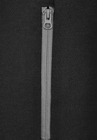 Svart tyg med en vertikal grå dragkedja, med en slät textur och färdiga kanter. Dragkedjan är av metall med en rund dragflik.