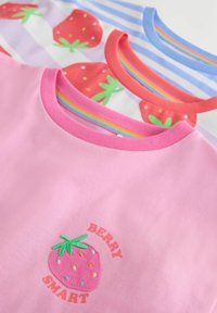 Tres camisetas para niños con cuello redondo, dos a rayas con fresas y una rosa con una fresa bordada y el texto "Berry Smart".