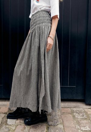 Langer schwarz-weiß karierten Rock mit gerafftem Bund, kombiniert mit schwarzen Stiefeletten mit Schnallen. Strukturierter Stoff fällt elegant.