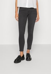 Zwarte slim-fit denim jeans met een soepele textuur en een klassiek vijf-pocket ontwerp, gecombineerd met zwarte textuur loafers met een chunky zool.