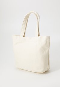 Sac en toile en couleur crème, doté de deux poignées plates, d'une forme rectangulaire structurée et d'une texture unie avec des coutures minimales.