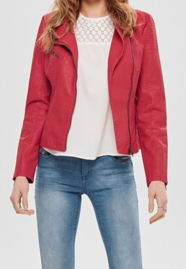 Veste de motard en simili cuir rouge avec fermeture éclair asymétrique, épaules texturées et coupe ajustée, associée à un haut blanc et un jean bleu.