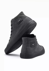 Zapatillas altas de tela gris oscuro con suelas de goma negra. Las características incluyen un diseño con cordones y un parche rectangular con el logo en el lateral.