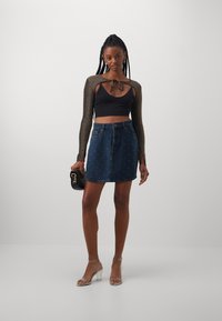 Fekete crop top fényes kiegészítőkkel, farmer rakott szoknya fehér díszítéssel, fekete táska és átlátszó, magassarkú szandál.