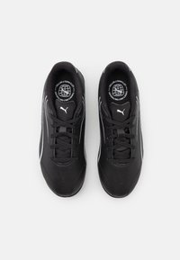 Et par sorte Puma sneakers med snørebånd og hvidt logo, set ovenfra på en simpel hvid baggrund.