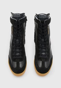 Sneaker alte nere in pelle e camoscio, con una finitura testurizzata, dettagli perforati e suola in gomma color caramello.