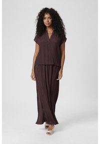 Tenue deux pièces fluide marron avec un haut ample à encolure en V et manches courtes, associé à un pantalon large, fabriqué dans un tissu léger.