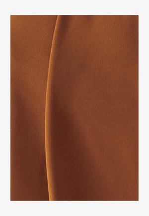 Hnedá texturovaná látka s viditeľným zvislým záhybom vytvára jemné tiene a svetelné variácie na povrchu látky.