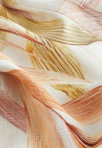 Tissu léger et texturé présentant des traits abstraits dans des teintes d'orange, d'or et de rose clair, sur fond crème.