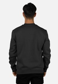 Sudadera negra con cuello redondo, puños y bajo acanalados. Tejido de textura lisa sin patrones ni adornos visibles.