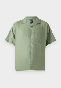 Camisa verde de manga corta con botones, hecha de una tela ligera, que presenta un bolsillo delantero y un diseño de cuello clásico con botones en contraste.