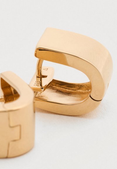 Σκουλαρίκια από μεταλλικό υλικό σε χρυσό τόνο με κομψό, κυρτό σχέδιο. Η επιφάνεια είναι λεία και γυαλισμένη, με μεντεσέ και κλείσιμο για ασφαλές κούμπωμα.