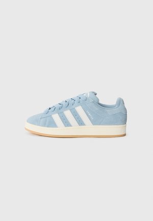 Lyseblå Adidas Campus ruskindssneaker med hvide striber og cremefarvet sål vist fra siden på ensfarvet baggrund.