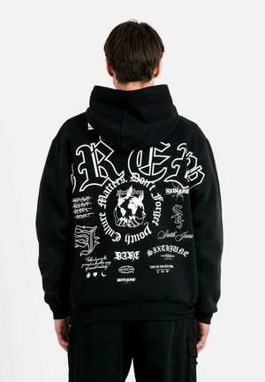 Sudadera negra con diversas impresiones gráficas y texto en blanco. El material parece suave, con un corte relajado y capucha con cordón.