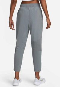 Grijze sportbroek met een elastische tailleband, taps toelopende pijpen, mesh panelen bij de knieën en een gladde stoftextuur.