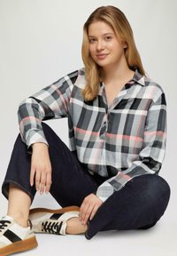 Gechikt shirt met grijs, zwart en roze kleuren; met knopen; zachte stof; lange mouwen. In combinatie met donkere jeans en sneakers.