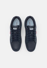 Navy blue sneakers with a smooth leather upper, white rubber sole, lace-up design, and a small red label on the side.