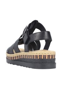 Sandale en cuir noir avec des sangles croisées, boucle réglable et une semelle superposée avec une base noire texturée et un accent tissé naturel.