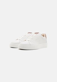 White leather sneakers with a smooth finish, rounded toe, and flat rubber sole. Features brown accents on the heel and logo detail.