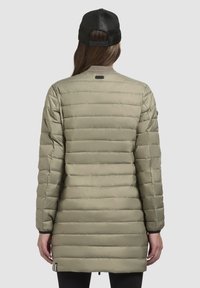 Olivgrön pufferjacka med horisontella s�ömmar, långa ärmar och rundad krage. Bakvy visar logotypen vid nacken och elastiska ärmslut.