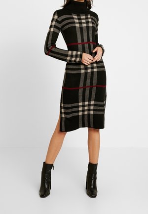 Robe noire en tricot avec un col roulé côtelé haut. Présente un motif à carreaux beige et rouge, des manches longues et des fentes latérales à l'ourlet.