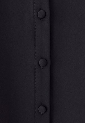 Black fabric with a smooth texture featuring a vertical row of six circular buttons. The buttons are matte and aligned with the fabric seam.