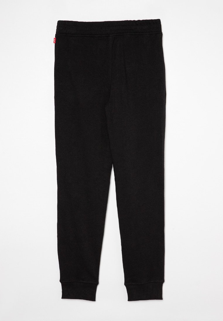 Jogging en coton noir avec une taille élastique et des poignets côtelés, présentant une petite étiquette rouge sur le côté. Texture lisse.