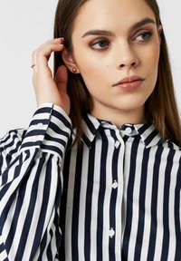 Navy and white striped button-up shirt with long sleeves, featuring a collared neckline and round white buttons, showcasing a smooth texture.