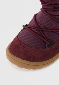 Calzado con un upper de gamuza marrón y tejido texturizado, con una suela de goma flexible y cordones en contraste, adecuado para su uso en exterior.