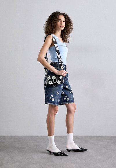 Sort blomsterprintet crossover taske med sølvhardware; båret med en lysblå tanktop, denimnederdel og sorte spidse sko med lav hæl.