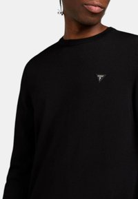 Zwarte sweatstof met lange mouwen, gemaakt van katoen, met een klein driehoekig logo-opgenaaid op de borst. Eenvoudig ontwerp met een ronde halslijn.