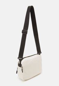 Hvid stof crossbody taske i rektangulær form, med sort justerbar rem og lynlåslukning. tekstureret overflade uden mønstre.