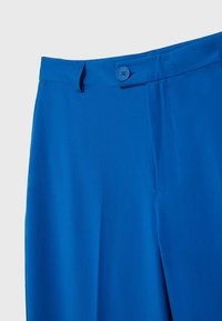 Helle blaue Hose mit flachem Vorderteil, Knopfverschluss am Bund und tailliertem Schnitt. Glattes Material und dezente Seitentaschen.