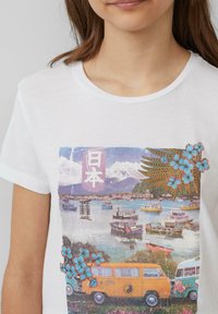 Weißes Baumwoll-T-Shirt mit einem grafischen Druck von Booten, Blumen und japanischem Text, im Hintergrund ein vintage Transporter und der Mount Fuji.