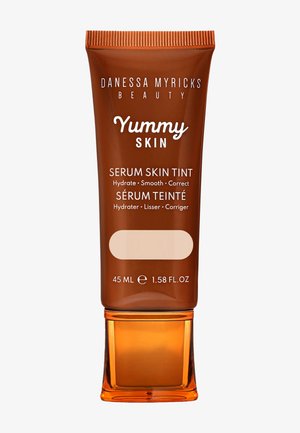 Siero per la pelle Yummy Skin Tint, 45 mL, in un tubo marrone squeeze con un tappo arancione trasparente, presenta un testo bianco e un'anteprima ovale del colore in basso.