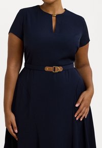 Vestido azul marino con mangas cortas, escote en forma de lágrima y un cinturón marrón con una hebilla dorada. Tela suave con una falda fluida.