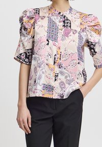 Blouse à manches courtes en tissu semblable à la soie, présentant un mélange de motifs pastel, des manches bouffantes, une fermeture à boutons sur le devant et un col mandarin.