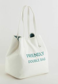Sac fourre-tout blanc en matériau synthétique texturé, doté de poignées doubles et imprimé "FRIENDLY DOUBLE BAG" en turquoise. L'intérieur est turquoise.