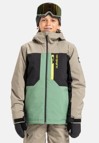 Skijas met een mix van groen, zwart en beige kleuren, voorzien van een gele rits, een verstelbare capuchon en fleece gevoerde zakken.