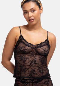 Zwarte kant camisole met dunne bandjes, bloemenpatroon en een gegolfde rand. Textuur, semi-doorzichtig materiaal met een relaxed fit.