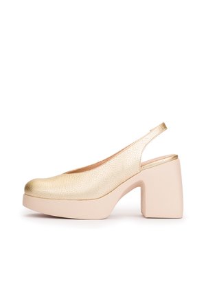 Zapato tipo slingback con textura dorada, tacón grueso beige con plataforma, punta redondeada y correa trasera abierta.