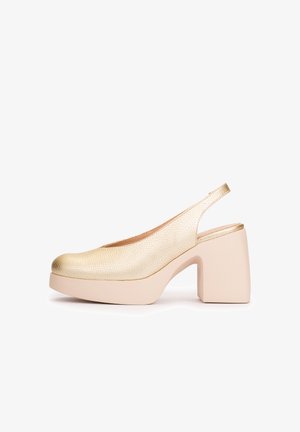 Zapato tipo slingback con textura dorada, tacón grueso beige con plataforma, punta redondeada y correa trasera abierta.