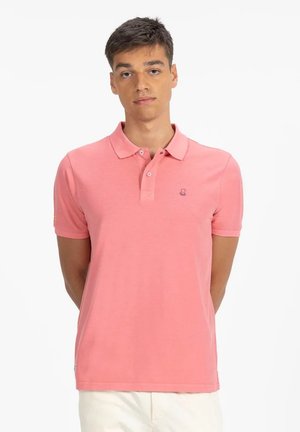 Camisa polo rosa de tejido suave con cuello, tapeta de tres botones y un pequeño logo de pulpo en el pecho.