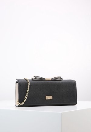 Zwarte rechthoekige clutch met gouden kettingriem, strikdetail bovenop en een kleine gouden merkplaat aan de voorkant, geplaatst op een witte ondergrond.