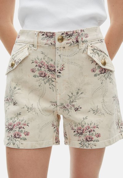 Pantalones cortos de mezclilla con estampado floral en beige con rosas rosas y verdes. Presentan detalles en botones dorados y bolsillos de solapa.
