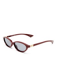 Burgundy sunglasses with round lenses and a glossy finish. Gold accents at the temples enhance the sleek design. Frames have a slightly pointed shape.