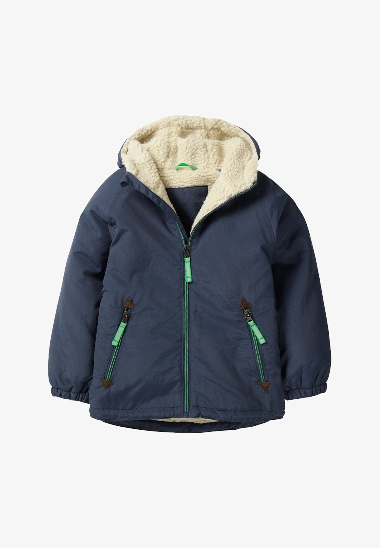 Marineblauwe jas met een fuzzy crèmekleurige fleece voering, voorrits en twee ritszakken, met groene accenten en bruine hardware details.